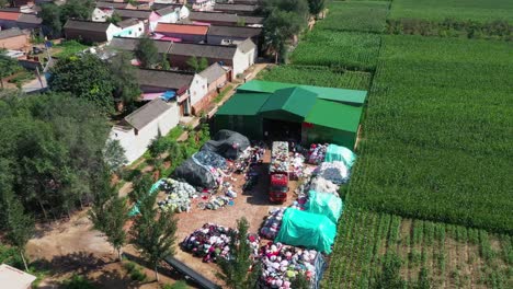 a-truck-unloading-old-clothes-for-recycling-in-a-Hebei-Village,-sunny-day-aerial-shot-in-China