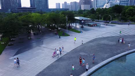 Aerial-Shot-of-a-Man-Jogging-in-a-Big-Park-with-Skyscrapers-in-the-Background-on-a-Cloudy-Day,-Hangzhou,-China