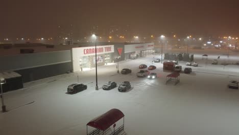 beautiful-nighttime-drone-footage-over-a-parking-lot-near-a-shopping-mall-during-the-blizzard-in-the-city-of-Toronto-in-Canada