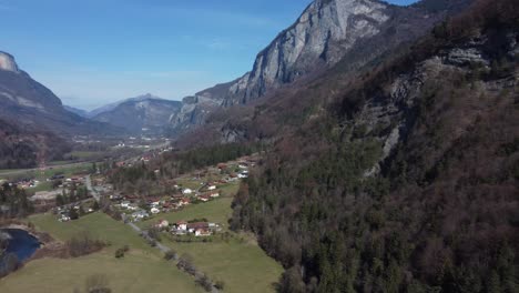 Aerial-panning-right-from-Oëx-village-to-Arpenaz-waterfall,-Sallanches,-Haute-Savoie,-french-Alps