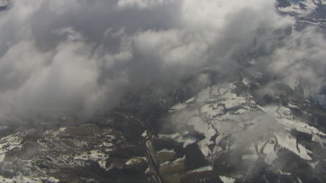 Aerial-shot-overhead-clouds-looking-down-on-the-snow-covered-landscape-below