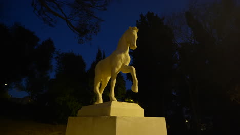 Ornate-white-marble-horse-sculpture-illuminated-in-Barcelona-park-at-night