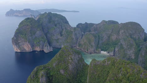 Aerial-view-above-the-lush-limestone-rock-formations-in-the-Andaman-sea-of-Ko-Phi-Phi-Leh-looking-towards-the-Ko-Phi-Phi-Don-islands-at-sunset-with-no-tourists-in-sight