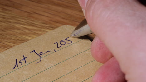 Person-hand-write-future-date-of-2058-on-paper-notebook,-close-up-view