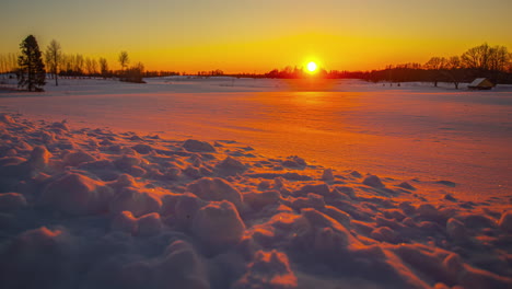 Wunderschöner-Orangefarbener-Sonnenuntergang-über-Einer-Winterlandschaft-Mit-Bäumen-Am-Horizont