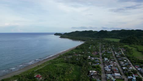Aerial-Overhead-Drone-shot-of-Quaint-Barangay-town-with-Calm-Sea-in-background-and-Lush-Foliage-in-Catanduanes,-Philippines
