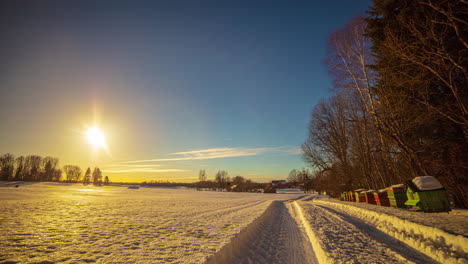 Eine-Untergehende-Gelbe-Sonne-Vor-Einem-Blauen-Himmel,-Wo-Kleine-Weiße-Wolken-über-Eine-Winterliche-Landschaft-Ziehen