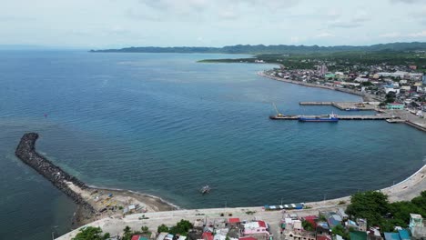 Atemberaubende-Luftaufnahmen-Des-Hafens-Von-Catanduanes-Fangen-Die-Geschäftige-Stadt,-Das-Blaue-Wasser-Und-Den-Malerischen-Wellenbrecher-Ein-–-Perfekt,-Um-Den-Handel-Und-Die-Schönheit-Der-Küste-Zu-Präsentieren