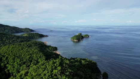 Cinematic,-Approaching-Aerial-View-of-white-lighthouse-atop-tropical-island-mountain-revealing-amazing-view-of-pristine-ocean-waters-and-lush-jungles