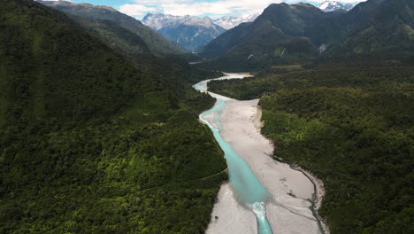 Aerial-forward-view-of-a-gorge-in-green-mountains-and-an-azure-river-running-through-it