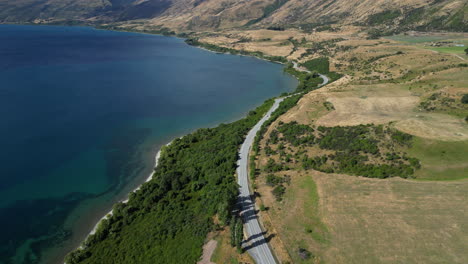 Scenic-lake-coastline-road-in-New-Zealand,-aerial-drone-view
