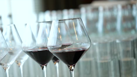 Sanfte-Hand-Nimmt-Ein-Durchsichtiges-Glas-Rotwein-Aus-Anderen-Gläsern