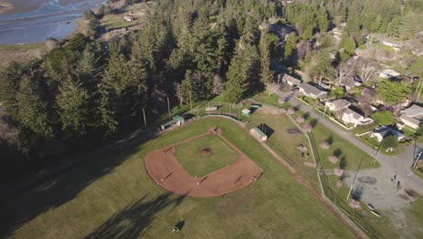 Beautiful-4K-aerial-shot-looking-down-at-local-baseball-field-with-players-in-Bandon,-Oregon