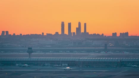 Zeitraffer-Sonnenuntergang-Hinter-Den-Skyline-Türmen-Von-Madrid-Und-Der-Silhouette-Des-Flugsicherungsturms-Des-Flughafens-Barajas-Während-Des-Farbenprächtigen-Sonnenuntergangs