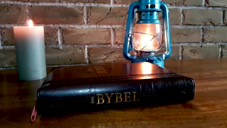 Geschlossene-Bibel-Auf-Tisch-Mit-Kerzen--Und-Öllampenrutschen