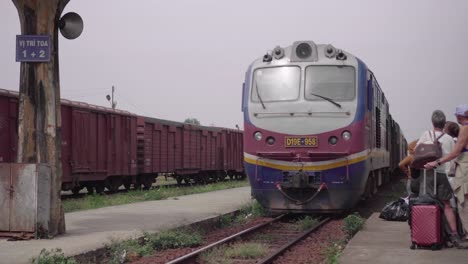 Tren-Expreso-De-Reunificación-De-Vietnam-Que-Llega-A-La-Plataforma-Con-Turistas-En-La-Estación-De-Binh-Thuan,-Vietnam