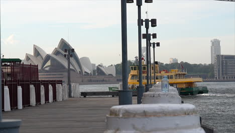 A-ferry-passes-by-a-boardwalk-in-Sydney-Harbour,-Australia