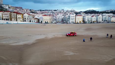 Aerial-View-Of-Red-Lifeguard-Vehicle-On-Nazare-Beach