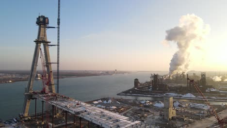 Gordie-Howe-bridge-construction-site-with-steaming-plant-in-foreground,-aerial-view