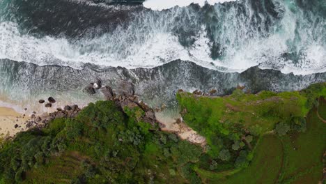 Overhead-drone-shot-of-tropical-beach-and-cliff-with-huge-sea-waves---Indonesia,-Asia