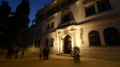 Menschen-Versammelten-Sich-Nachts-Vor-Dem-Beleuchteten-Klassischen-Antiken-Haus-Im-Barcelona-Park