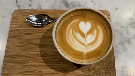 Primer-Plano-De-Una-Taza-De-Café-Con-Arte-Latte-Elaborado-Por-Expertos-Encima,-Humeante-Y-Acogedor
