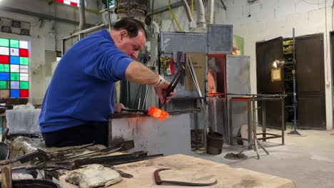 Glassmith-using-tools-to-create-bespoke-glassware-at-glassmaking-workshop