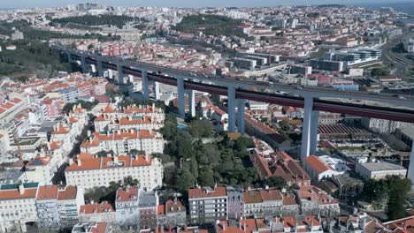 Experience-the-breathtaking-aerial-view-of-Lisbon-near-the-25th-of-April-Bridge,-where-cars-whizz-past-under-the-sunny-skies