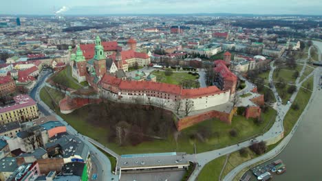 Establishing-dolly-shot-reveal-aerial-over-Wawel-Royal-Castle-by-the-river-Vistula-in-the-city-of-Krakow,-Poland,-with-the-city-center-in-the-background