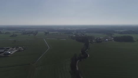 High-aerial-drone-shot-of-farmlands-and-town-with-tree-line-on-a-backroad
