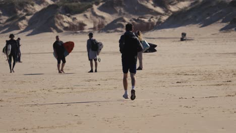 A-man-jogs-on-a-beach-full-of-surfers