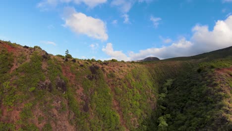aerial-motion-view-Over-steep-forested-hills-to-narrow-valley-and-distant-waterfalls-on-Molokai