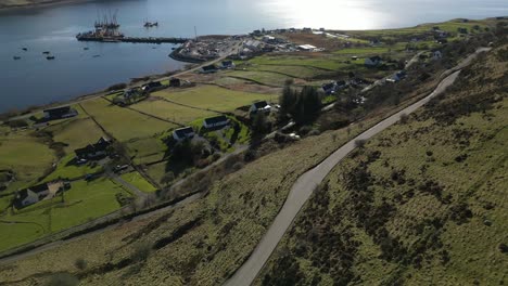 Flying-over-Highland-road-traffic-towards-fishing-port-at-Idrigil-Bay-Uig-Isle-of-Skye-Scotland