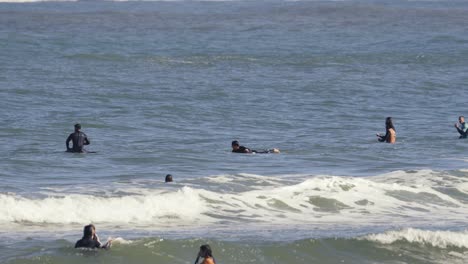 Group-of-beginners-surfers-trying-to-surf-in-shallow-water-on-small-waves