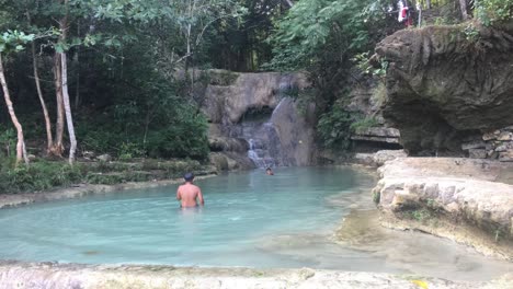 Local-indonesian-kids-play-in-a-beautiful-blue-fresh-water-river-pool-with-waterfall-in-java-island