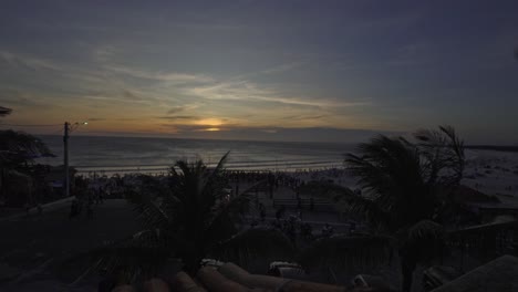 Sonnenuntergang-Am-Strand-Mit-Kokospalmen,-Die-Sich-Im-Wind-Wiegen,-Und-Menschen,-Die-Diesen-Moment-Der-Natur-Beobachten