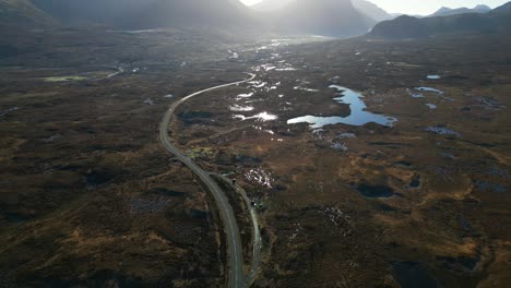 Pan-across-Scottish-Highland-road-and-wilderness-with-dawn-sunlight-reflecting-off-water-at-Sligachan-Isle-of-Skye