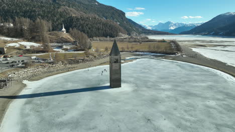 Drone-dolley-shot-to-the-Sunken-church-of-Graun-at-the-reschen-lake-with-alps-in-the-background