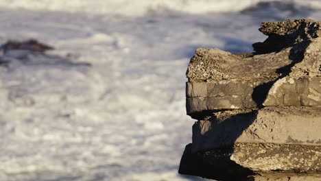 Eroded-stones-and-rough-ocean-waves-in-background,-Portugal-coast-near-Peniche
