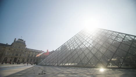 Famosa-Pirámide-De-Cristal-Del-Louvre-Mientras-Sale-El-Sol,-Se-Establece,-Toma-Panorámica
