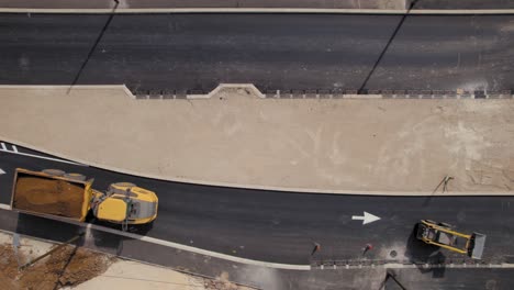 top-down-view-of-an-dump-truck-and-Skid-Steer-Loader-crossing-a-new-road-at-a-new-neighborhood-construction-site