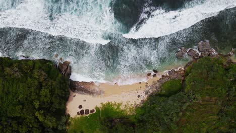 Static-drone-shot-of-white-sandy-beach-with-big-sea-wave