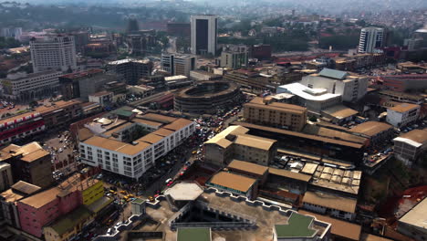Aerial-view-over-the-cityscape-of-Yaounde,-revealing-the-Hotel-Adamaoua-in-sunny-Cameroon---reverse,-drone-shot