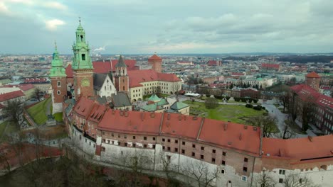 Slow-establishing-shot-over-the-walls-of-Wawel-Royal-Castle-in-Krakow,-Poland-moving-forward,-city-center-fortress-with-the-old-town-and-Cracow-skyline,-aerial