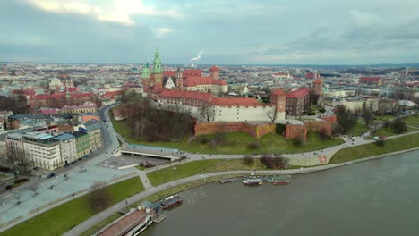 Side-dolly-shot-over-Vistula-rives-with-Krakow-Wawel-Royal-Castle,-city-center-fortress-with-the-old-town-and-Cracow-skyline