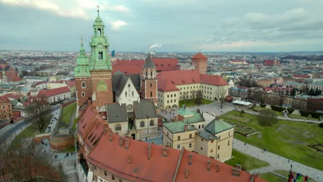 Slow-reveal-flying-backwards-over-Krakow-Wawel-Royal-Castle-moving-forward,-city-center-fortress-with-the-old-town-and-Cracow-skyline
