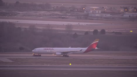 Seitenansicht-Eines-Abschleppwagens,-Der-Ein-Iberia-Flugzeug-Am-Flughafen-Madrid-Zieht