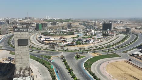 Aerial-View-Of-Zuraaco-Tower-Beside-Large-Roundabout-Near-Jinnah-Avenue-In-Bahria-Town,-Karachi
