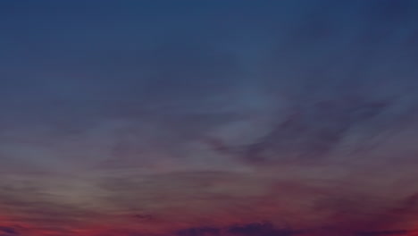 Sky-colored-from-blue-to-red-with-clouds-advancing-in-a-timelapse