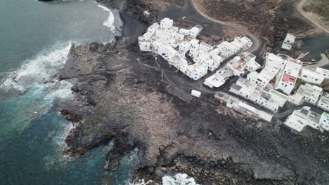 Topshot-of-the-Tenesar-village-in-Lanzarote,-Canary-Islands,-big-waves-crashing